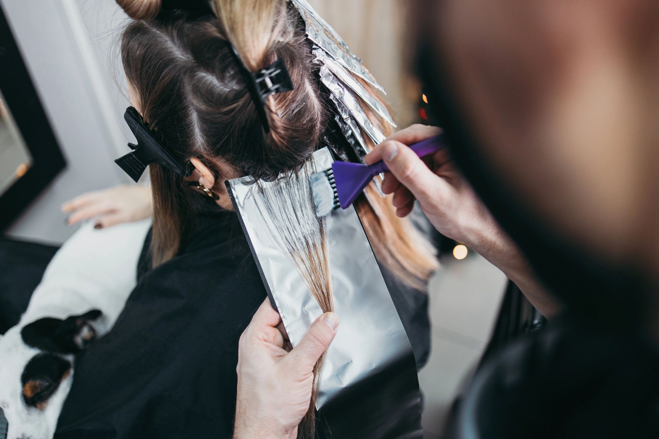 Stylist applying hair color highlights using foils