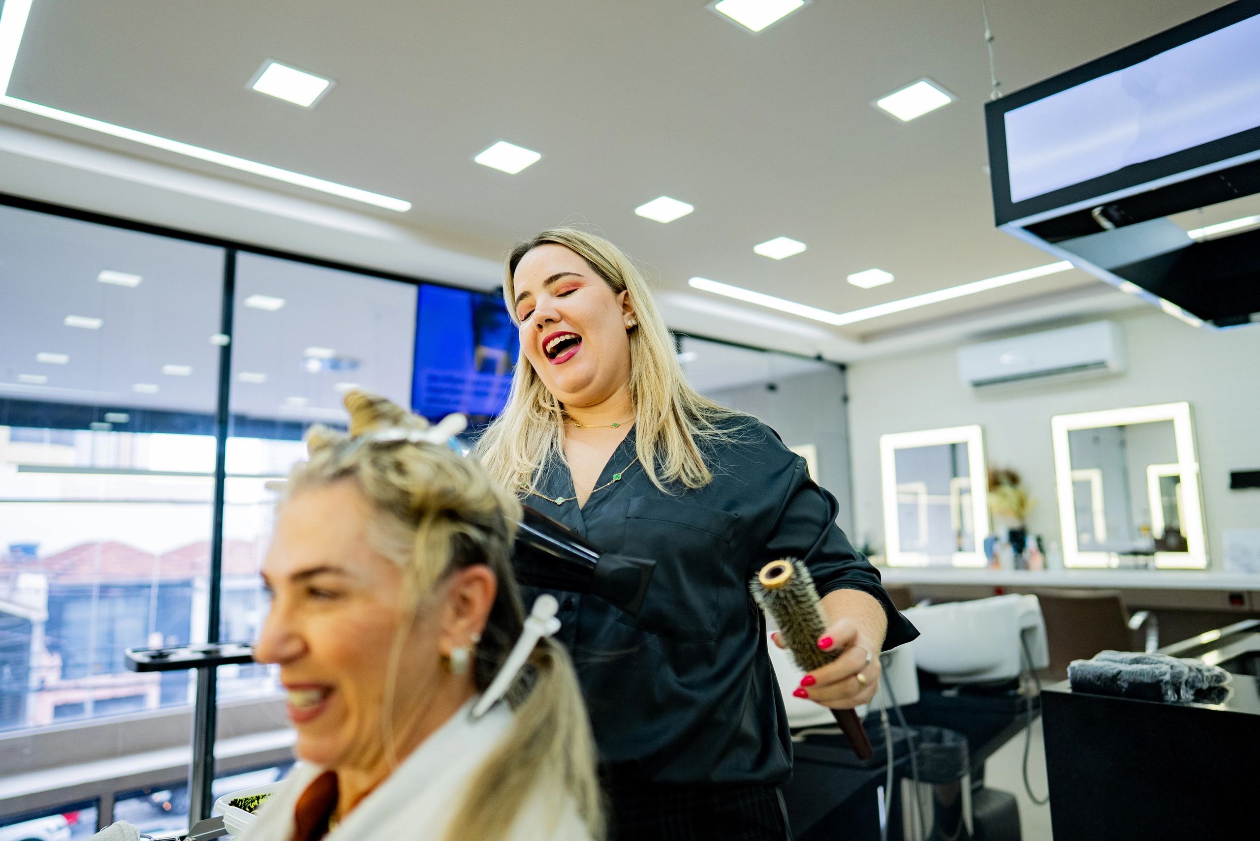 Stylist blow drying a client’s hair in a salon